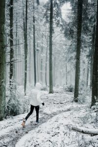Woman walking on a snowy forest trail supporting nervous system regulation through seasonal living and time in nature
