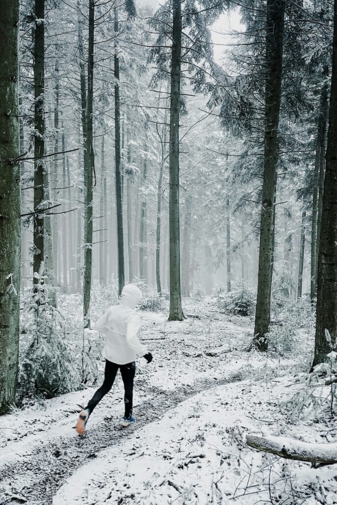Woman walking on a snowy forest trail supporting nervous system regulation through seasonal living and time in nature