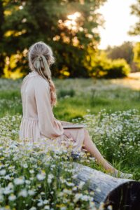 Woman reflecting in a field during late spring while creating space for what matters.